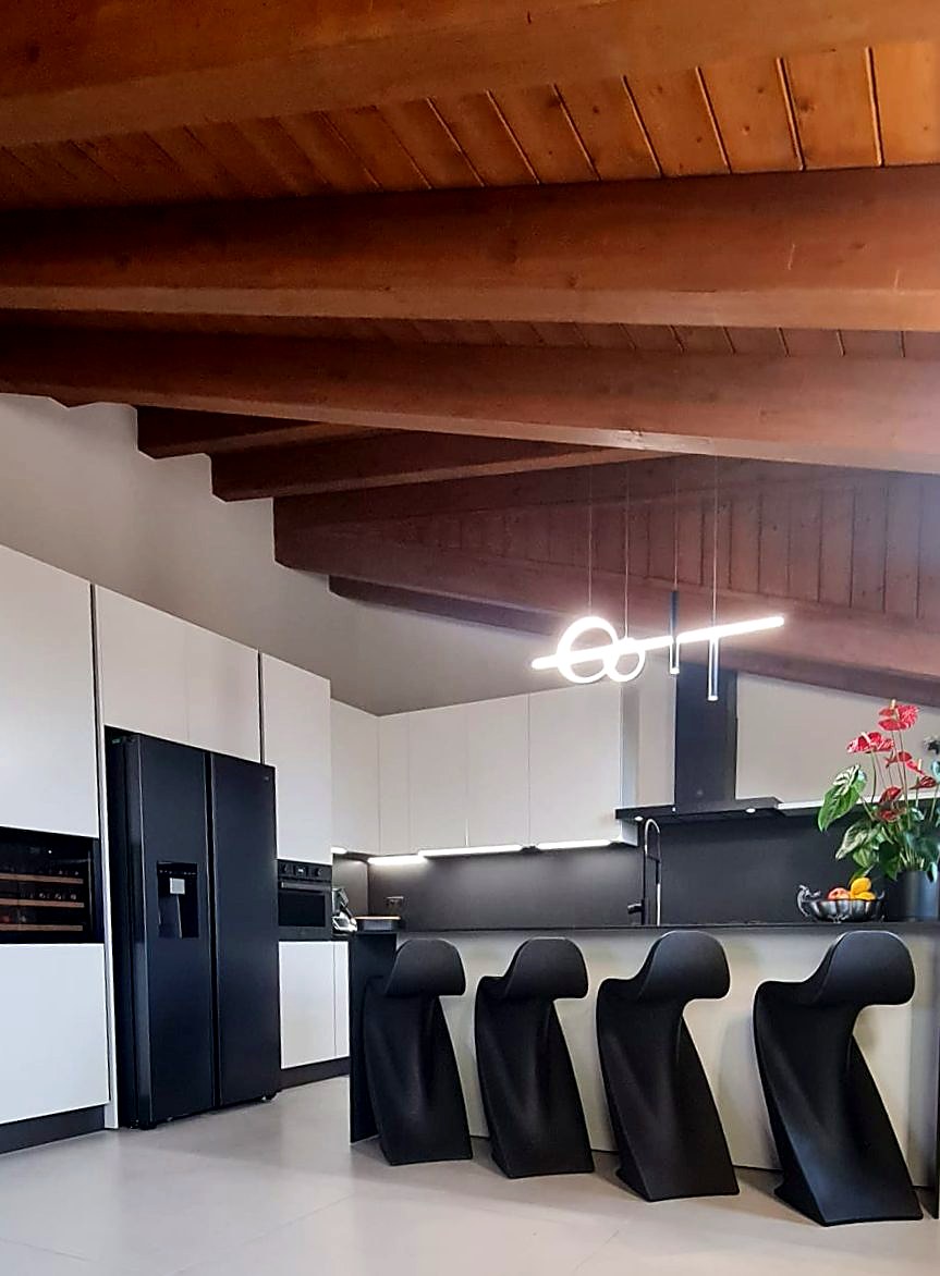 Cucina open space dell’attico sotto le travi in legno